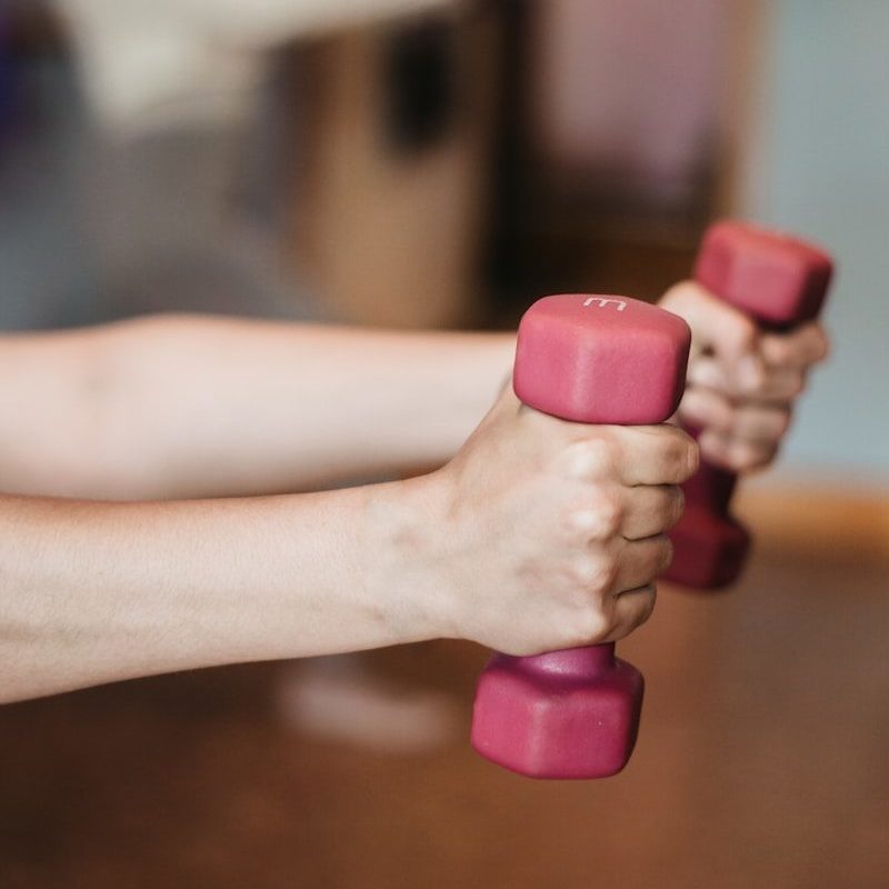 person holding pink and white dumbbells